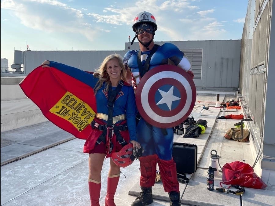 Two Fairfax County firefighters dressed as Supergirl and Captain America rappelled down the outside of Inova Children's Hospital on Tuesday to encourage young patients to persevere.