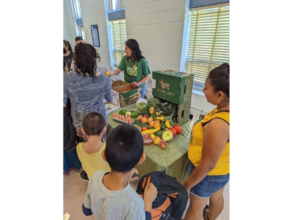 Valerie Vargas, a Seasonal Roots market manager from Rockville, distributes apples and peaches at the Viers Mill Elementary School Back-to-School Day.