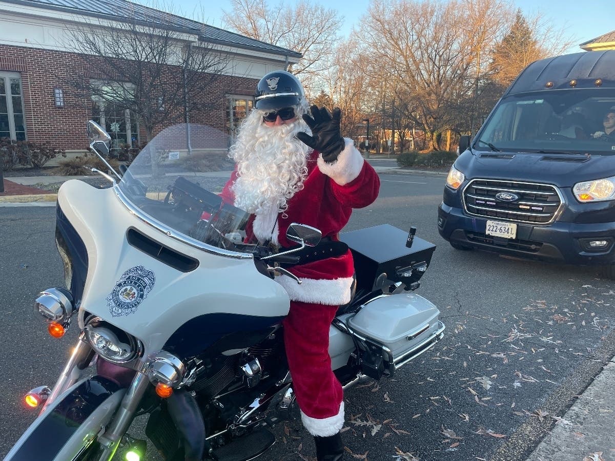 Motor Officer Santa Claus waves as he makes a stop Tuesday morning in the parking lot of the Sherwood Community Center in Fairfax City. 
