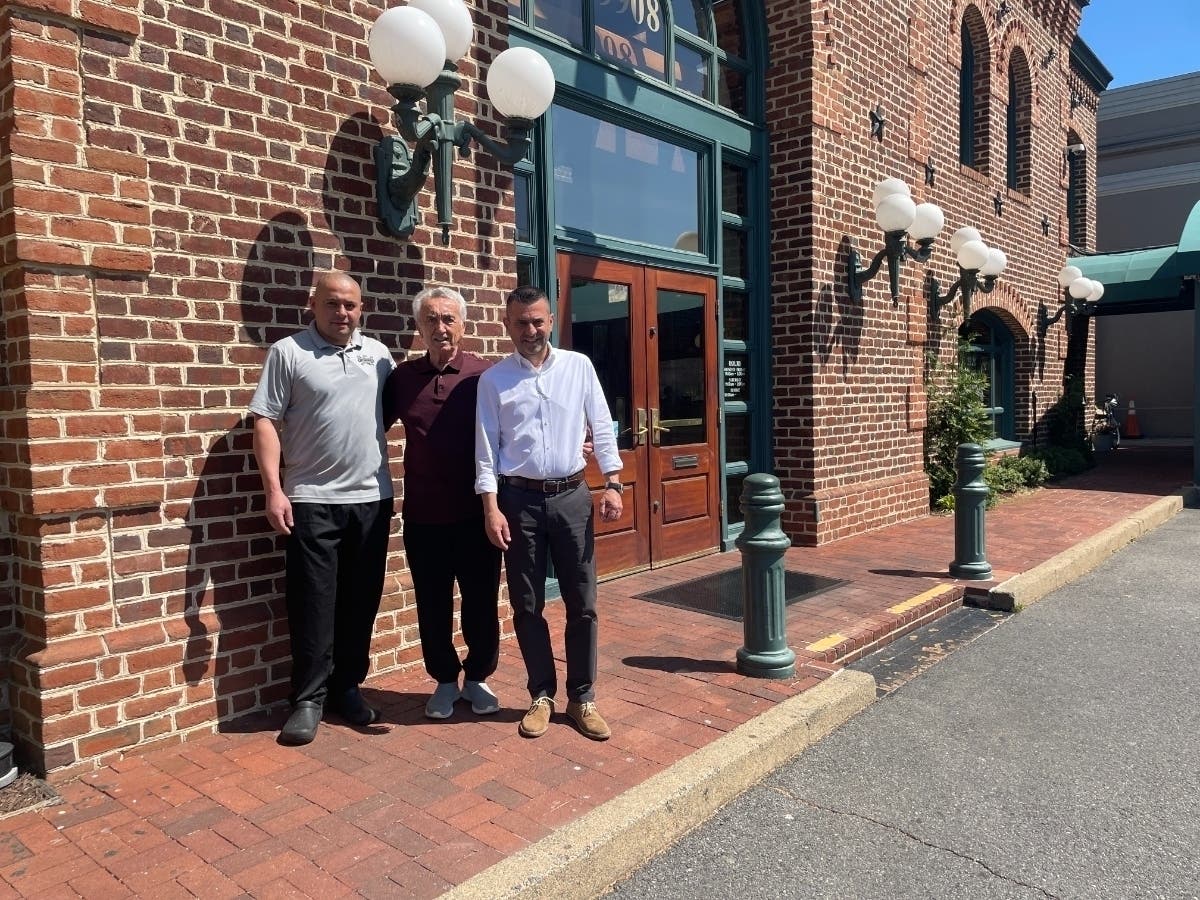 From left, chef Jorge Alvarez and P.J. Skidoos owners Cosmos Bells and Dimitri Paraskevopoulos pose for a photo outside the restaurant located at 9908 Fairfax Blvd. in Fairfax City.