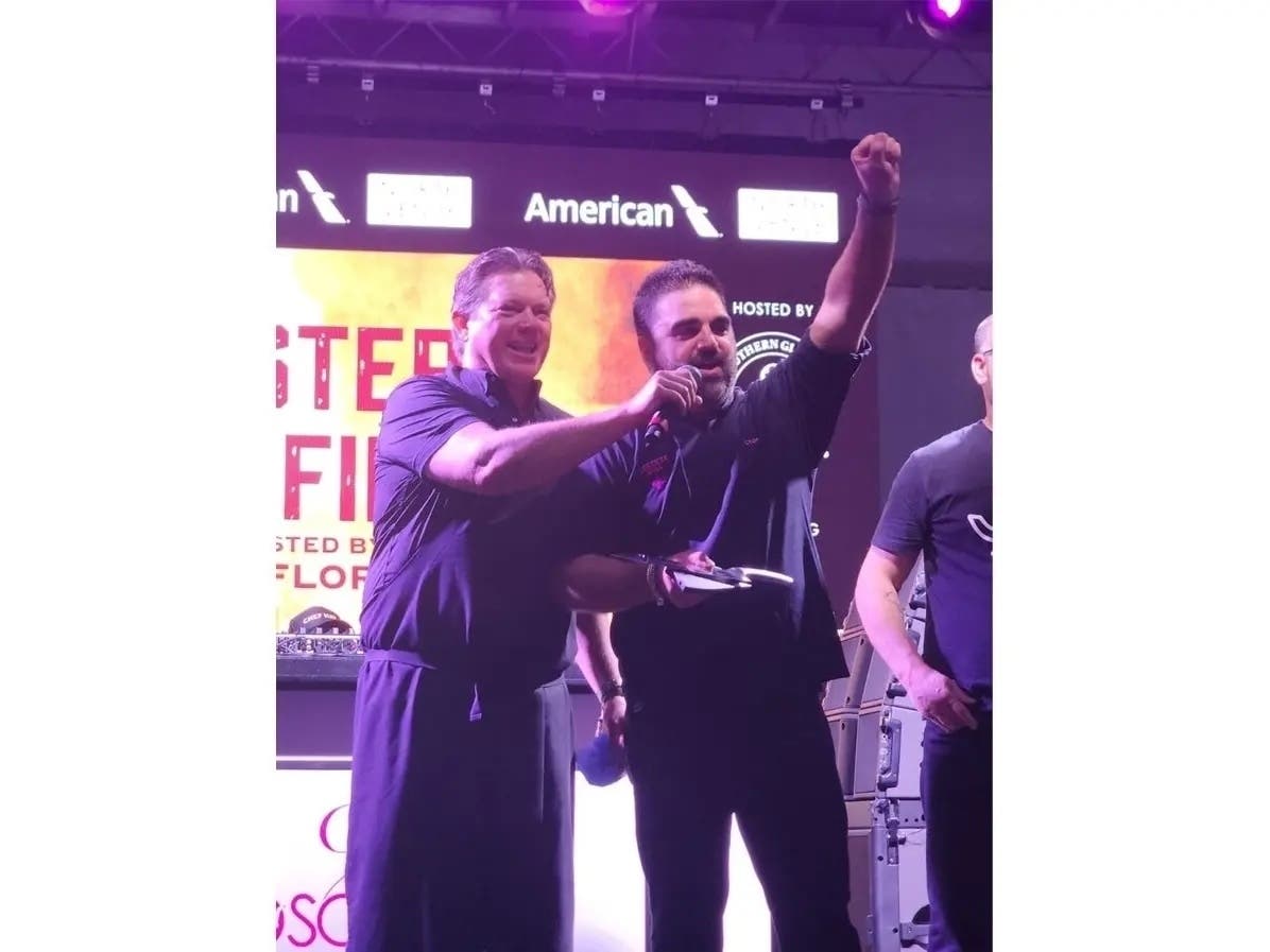 D.C.-area Chef Victor Albisu (right) reacts to winning the chef's choice award at the Masters Of Fire national grill competition hosted by Chef Tyler Florence of the Food Network (left).