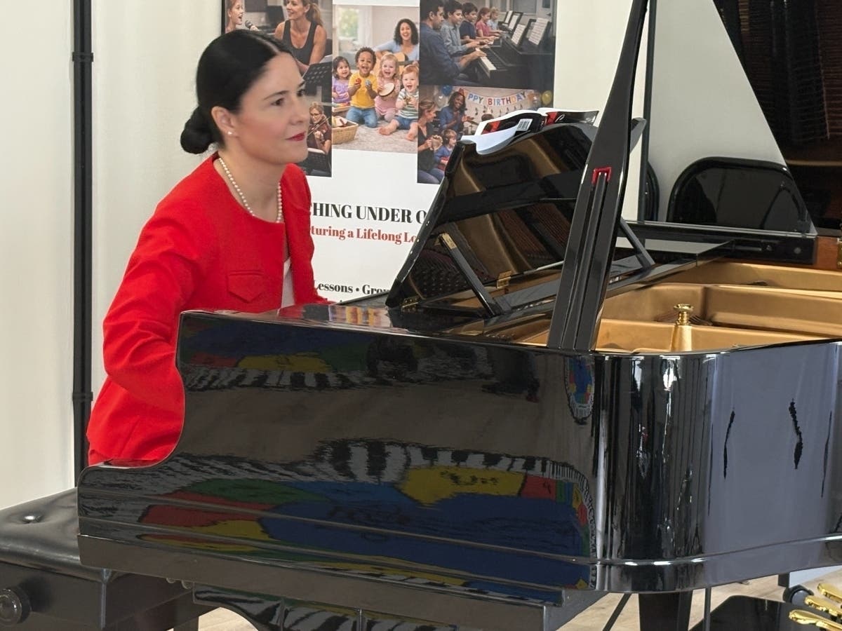 Owner Madalina Petric performs for Fairfax City officials, business leaders, and family members attending Thursday's ribbon-cutting ceremony for Music Love Academy at 10359 B Democracy Lane in Old Town.