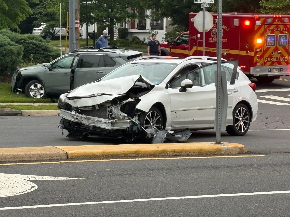 A white sedan involved in Thursday morning's crash on Main Street in Fairfax City stopped near the median at the Fairview Drive/Orchard Drive intersection. A gray SUV also involved in the crash came to a rest in the grassy area to the south.