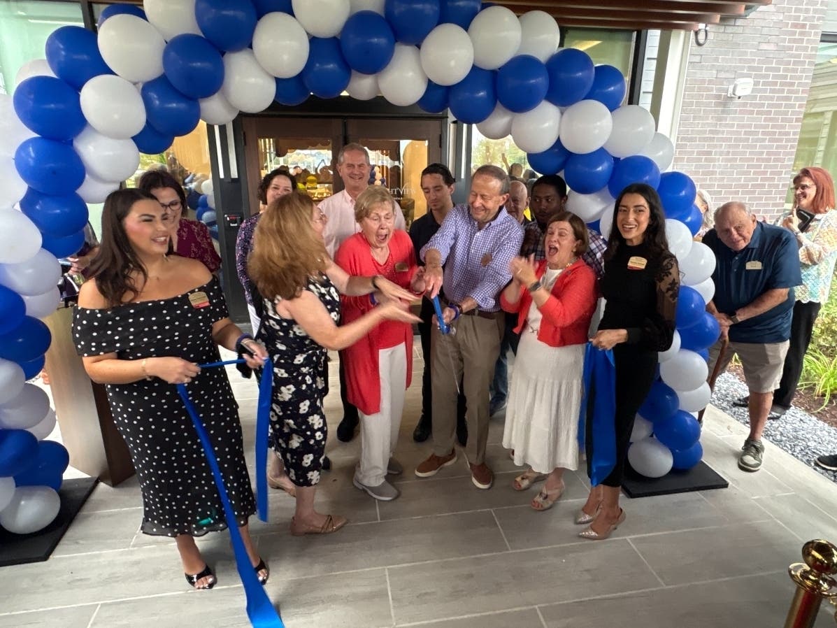 Gail and Chuck Mckeon, holding the scissors, cut the ribbon of the Brightview Northfax senior living center during Tuesday's grand opening ceremony. The Mckeons signed a lease in April 2025, making them the center's first residents.