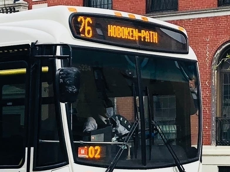 An NJ Transit bus driver wears a mask while driving down Washington Street.