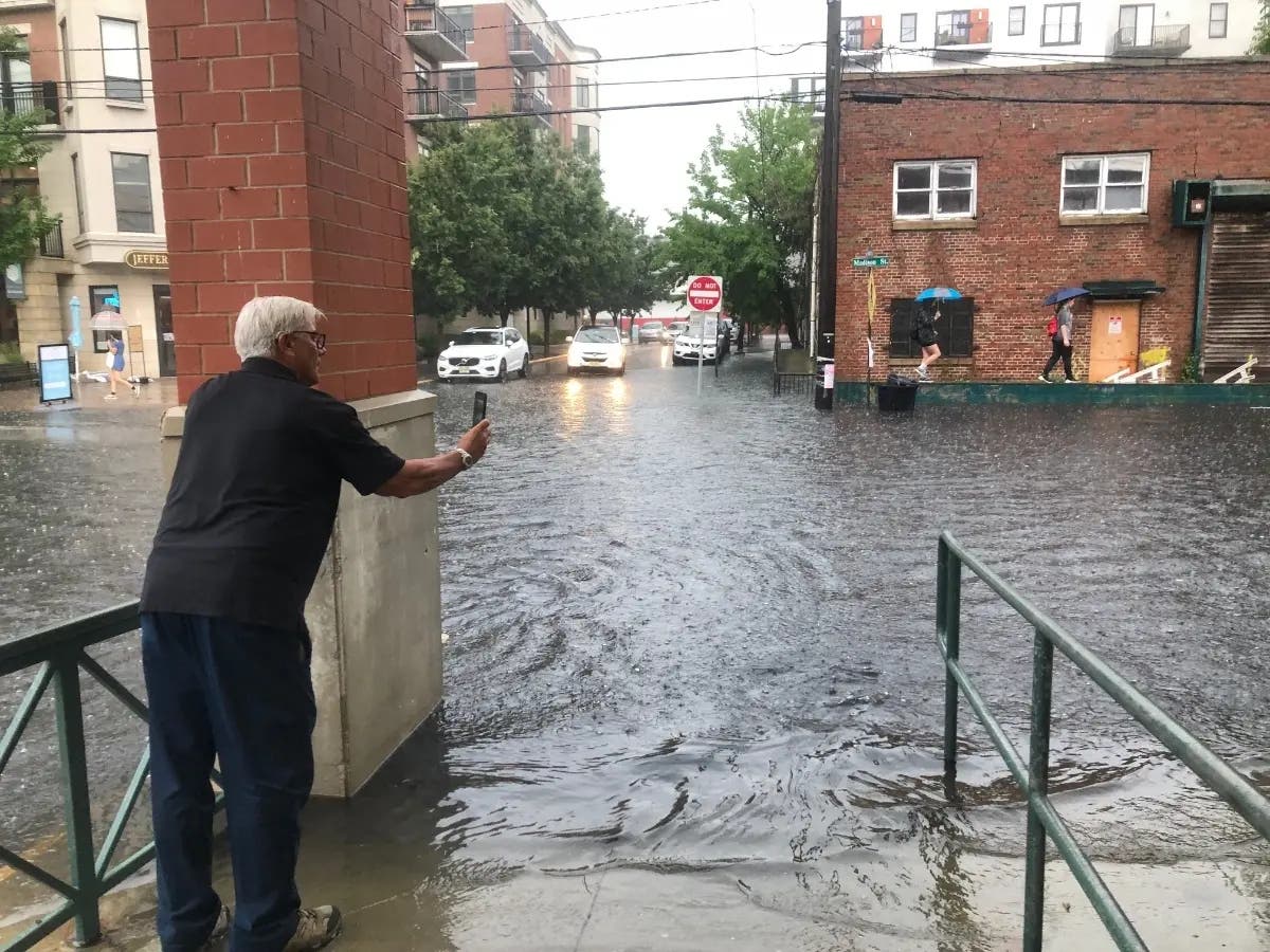 A man takes a photo of Tenth and Madison streets, outside the Hoboken ShopRite, during a rainstorm in summer 2021.