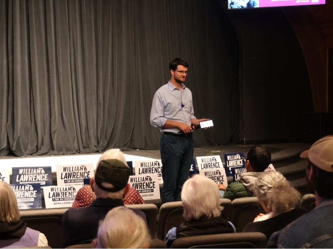 Democratic congressional candidate William Lawrence holds a microphone to his phone so that Sen. Bernie Sanders (I-Vermont) can speak to supporters gathered at Stage One at Sycamore Creek in Lansing on October 14, 2026