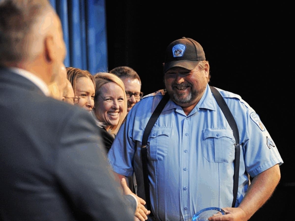 Eric Weigel, a corrections officer who has grown fresh produce used in a corrections facility kitchen, receives an award from Wisconsin Department of Corrections Secretary Jared Hoy at the Mitby Theater at Madison College.