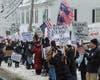 Protesters gathered for two hours, holding signs, speaking over bullhorns, and cheering as vehicles honked their horns on Baboosic Road.