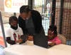 Atlanta Children’s Shelter (ACS) children using digital learning devices  provided by LogistiCare (left to right): Clayshaun, previous ACS kindergarten student; Aseelah Williams, Development Coordinator, ACS; Queen,  ACS kindergarten student.