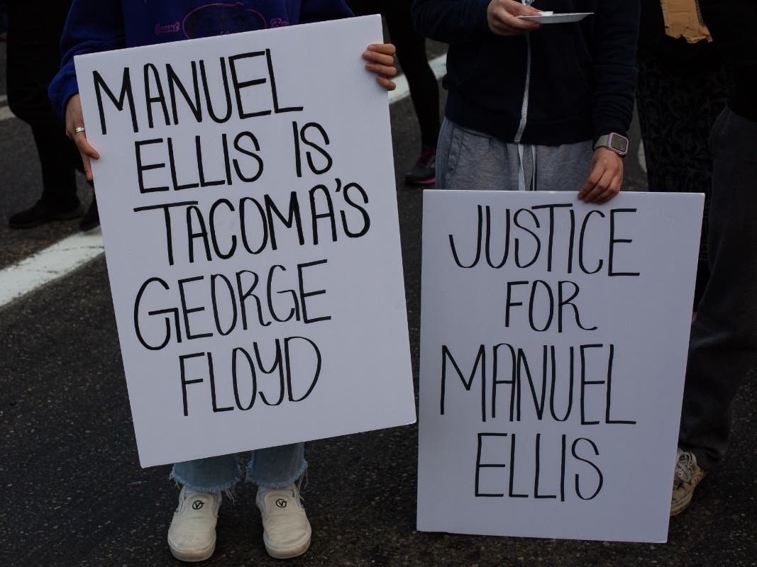 Signs seen at a vigil for Ellis in Tacoma on June 3. 
