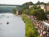 Spectators line the Kennebec River in Augusta as athletes compete in the 2025 IRONMAN 70.3 Maine triathlon. 