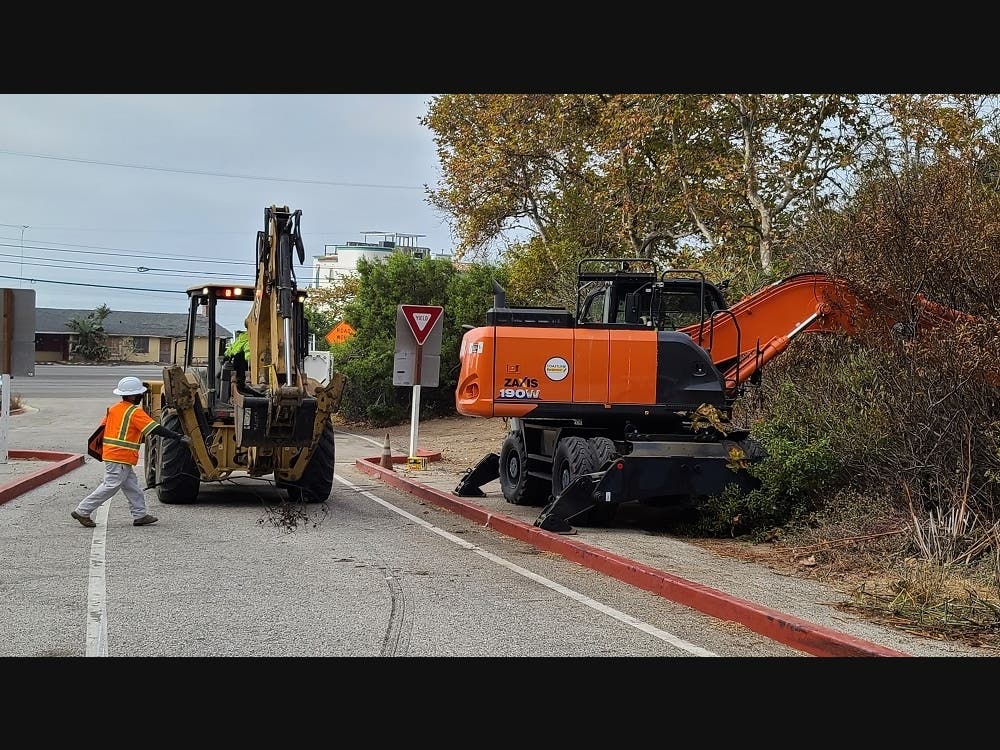 City workers clear out an encampment Tuesday from which three fires are believed to have originated.