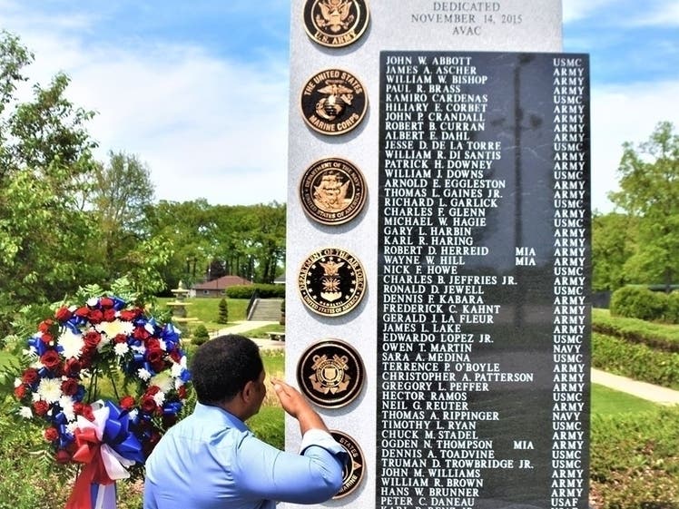 Aurora Mayor Richard Irvin salutes the men and women named on the Veterans Memorial Monument at Phillips Park Sunken Memorial Garden in honor of Memorial Day.