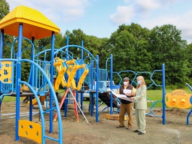 Mayor Nancy R. Rossi and Public Works Commissioner Tom J. McCarthy look over plans as a crew from ALZ Construction of Marshfield, Mass., finishes installing the new playground at Forest Elementary School on Wednesday, Sept. 16