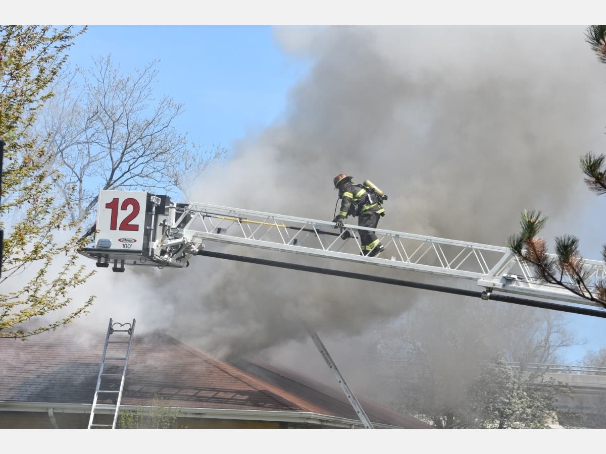 A Northbrook firefighter climbs a fire above a working fire Wednesday afternoon in the 4000 block of Timberlane Drive in Northbrook. 
