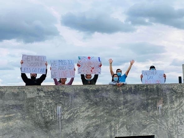 The family of a Deerfield mail carrier cheer for him Tuesday in the parking lot outside his hospital room. 