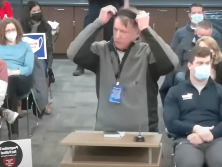 North Shore resident Mark Weyermuller puts a mask on his head during Monday's Glenbrook High School District 225 Board of Education meeting. 