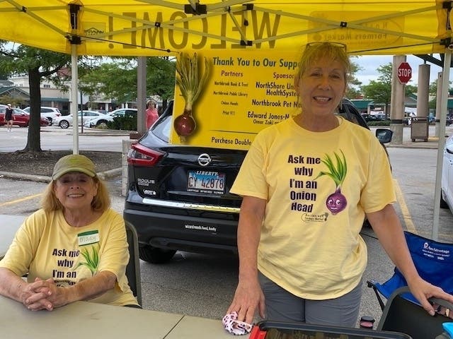 Mady Fern (seated) and Juliet Ziak meet customers at the market's welcome booth.