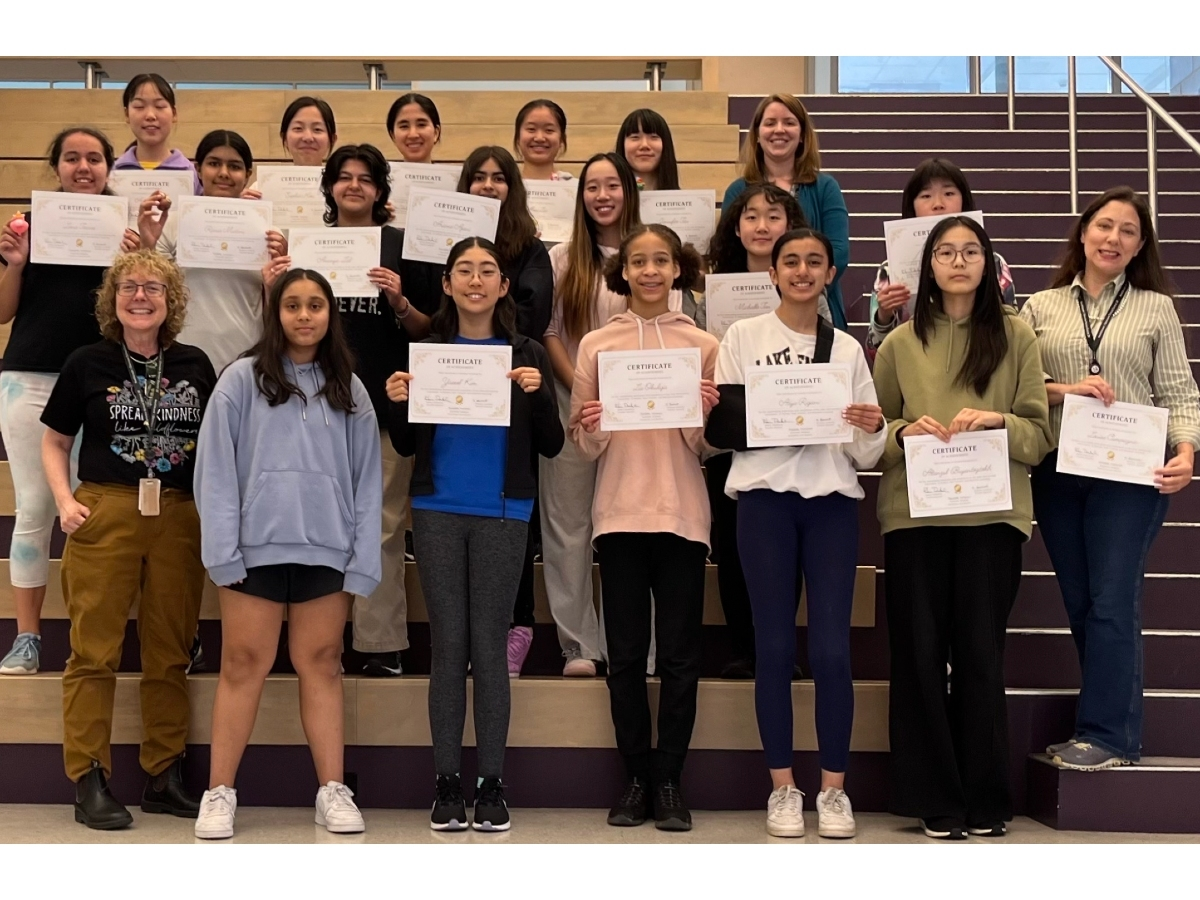 Students at Maple Middle School hold up certificates for completing the SheCanCode program. 