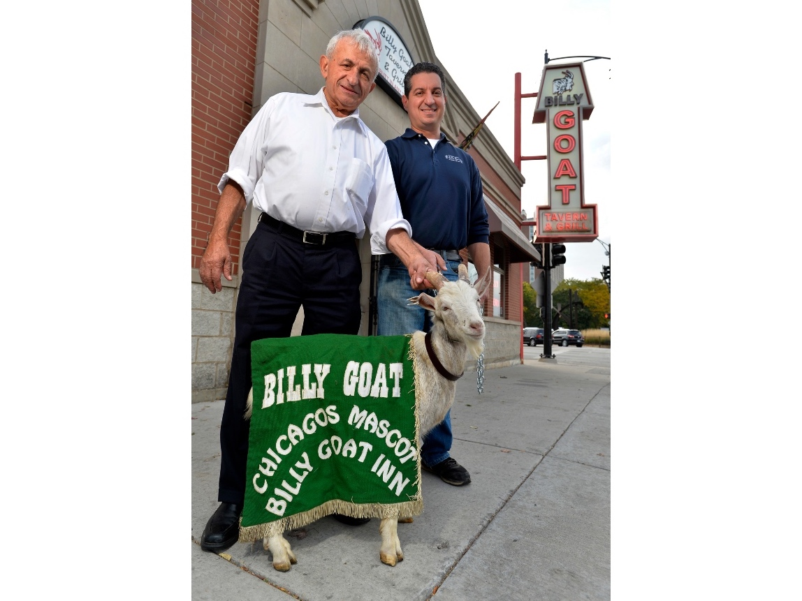In this Oct. 20, 2015, file photo, Billy Goat Tavern owners Sam Sianis, left, and his son Bill pose with "Billy" the goat outside their tavern on Madison Street in Chicago.