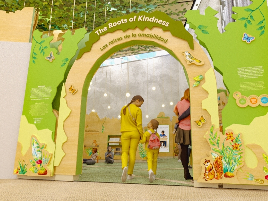 The exhibit is designed to resemble a nature-themed fairytale pop-up book, centered around a large tree and surrounded by several interactive areas.