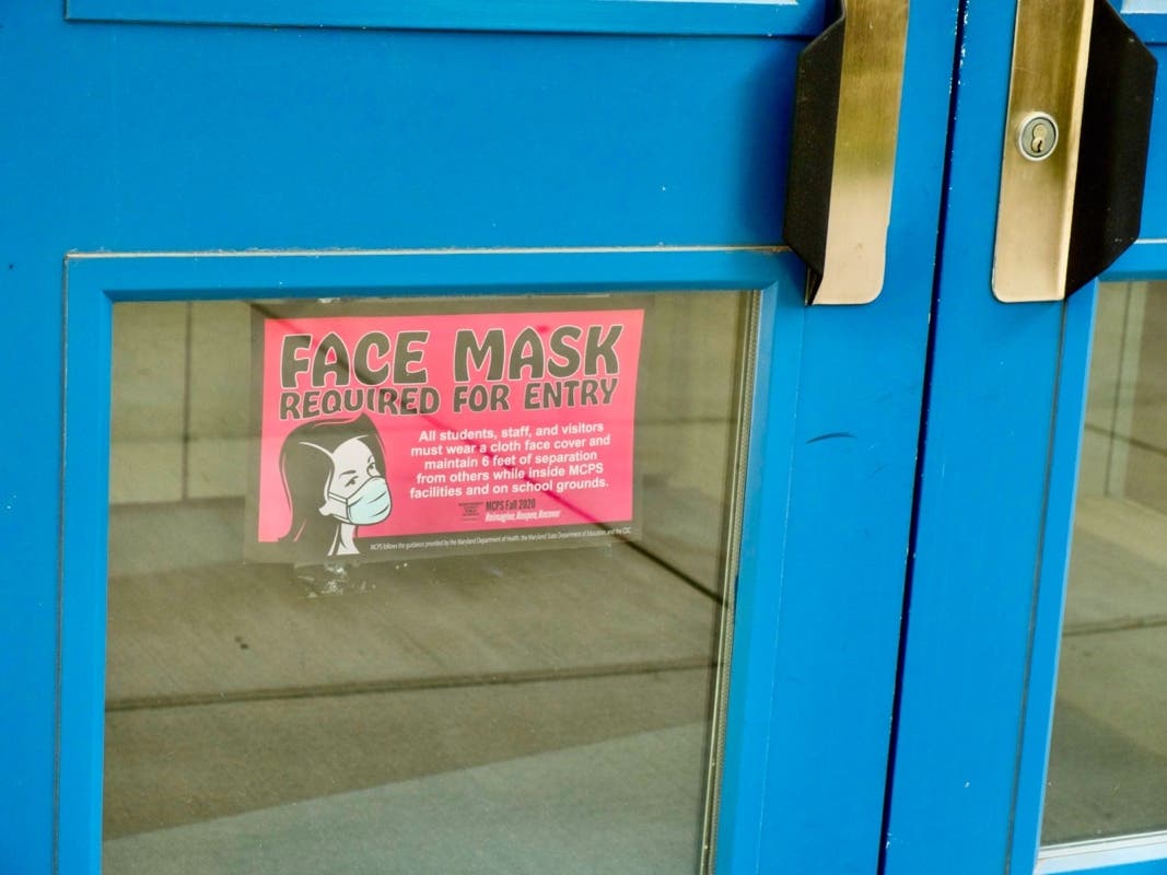A special education teacher at Paint Branch High School was placed on administrative leave for refusing to wear a mask. Pictured above: A sign asking visitors to wear a mask at the Montgomery County Public Schools headquarters in Rockville in June.