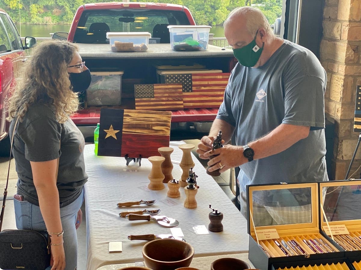 Mike Corbett, right, shows a pepper grinder he made to a potential customer Saturday morning at the Tuscaloosa Farmer's Market