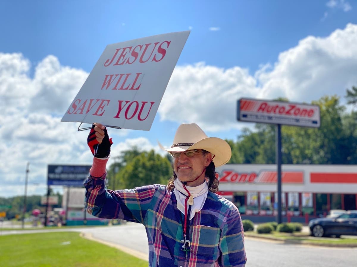 James David Bonner holds a sign facing the highway in front of Bojangles' in Five Points Monday morning. 