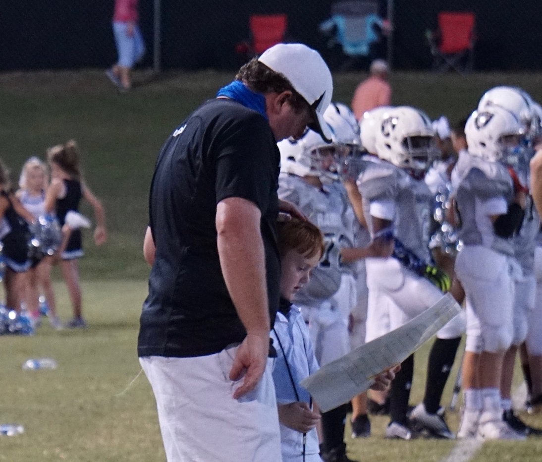 Coach Joe Cobb instructs Brady Dickey during youth tackle football play