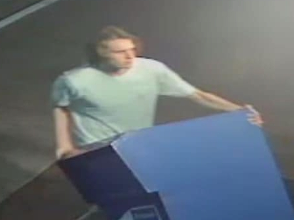 A surveillance photo of the suspect shows him using a donation box to attempt to break in to the Tuscaloosa Public Library on April 12
