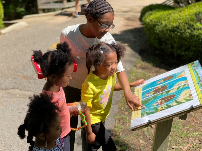 Abigail Barnes, Amelia Barnes, Ariel Barnes and Zoe Hall read one of the pages of the featured book at the first Tuscaloosa StoryWalk in April.