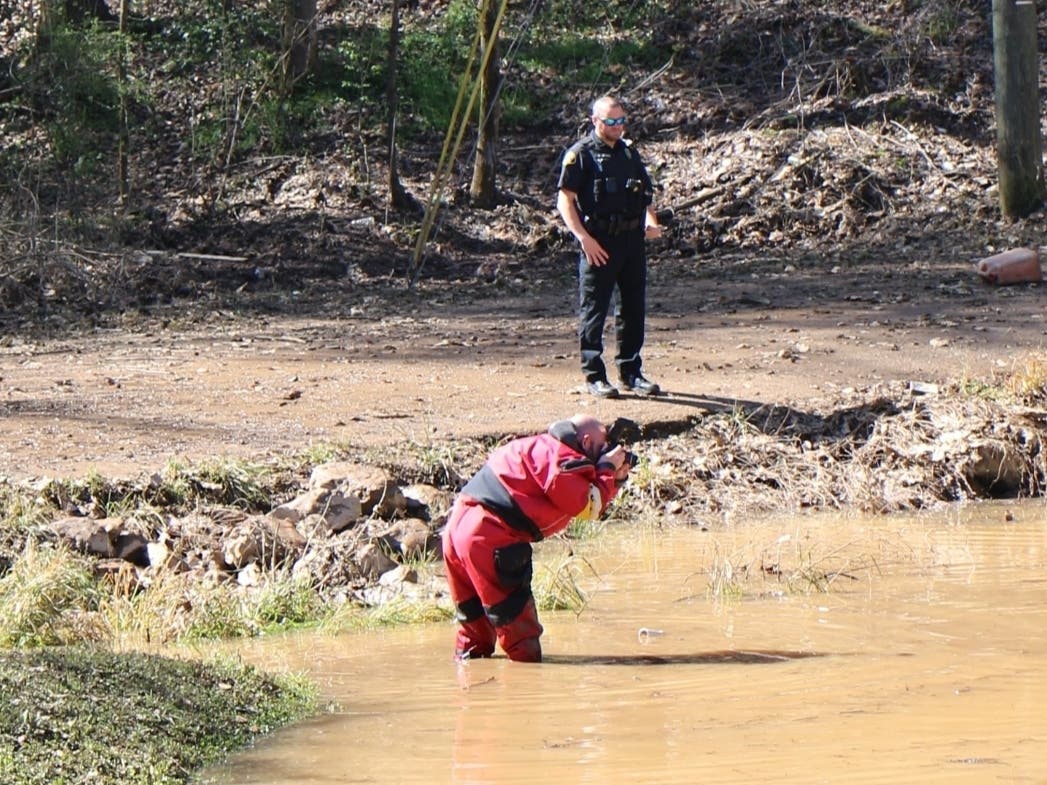 Investigators process the scene near Holt where the bodies of three individuals were found in a submerged vehicle. 