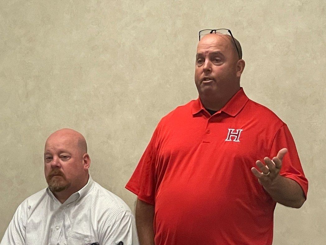 Hillcrest football coach Jamie Mitchell (standing) speaks during Wednesday's County Commission meeting and was joined by Hillcrest Principal Jeff Hinton. 