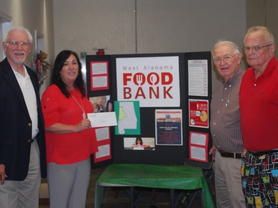 Glenn Taylor of the CFWA is shown making the presentation to Jean Rykaczewski, executive Director of the West Alabama Food Bank, as Sam Faucett and Roger Sayers look on