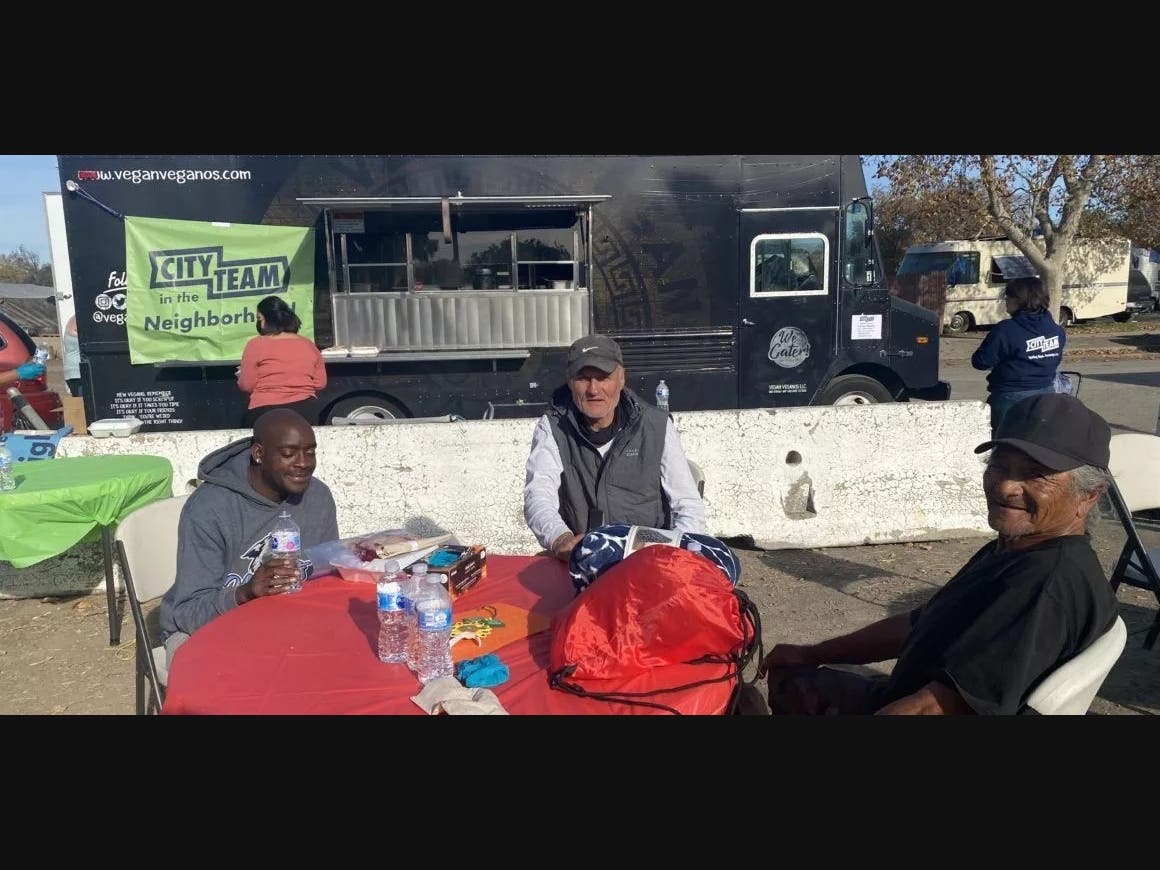 Unhoused residents Steve Beckwith, Alfonsas Sakauskas and George Villanueva enjoy a Thanksgiving meal at Columbus Park. 