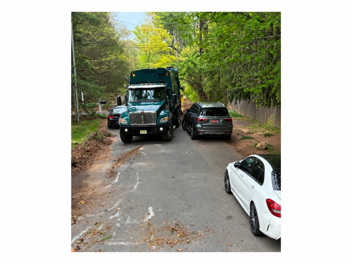  A photo showing vehicles parked on both sides of Hun Road with a trash truck attempting to pass