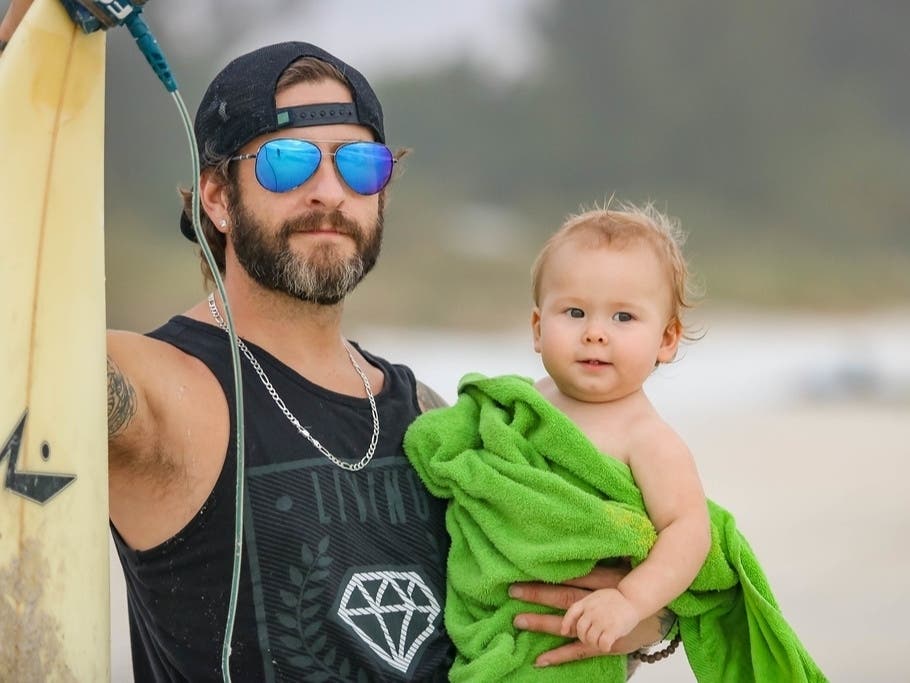 Kevin Greer, pictured with his 1-year-old son, Kylo, launched Kids with Boards to provide refurbished surfboards to families that couldn't afford their own and spread a lot of the gulf.