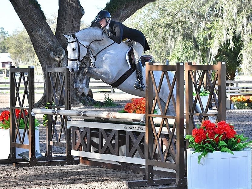 Hillary Schreiber Rheinheimer and her mount, Linda Brill's horse, Game On, fly effortlessly over an oxer jump while competing this winter in Florida.