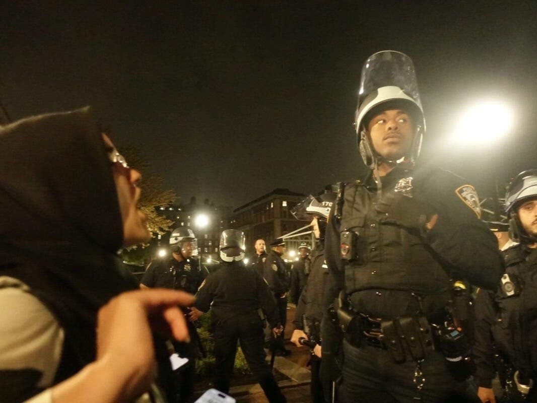 A protester faces off against an NYPD officer on the campus of Columbia University, April 30, 2024.