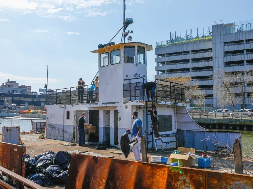 Volunteers clean off paint and trash before the Prudence Ferry can be sunk into the East River, April 4, 2026.