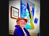 The artist known as bard sits below, her work on display at The Tea Leaf..