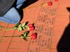 Family members lay red roses on the new bricks.