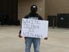 A Burnsville High School alum holds a sign as he directs students toward the football field for the rally.