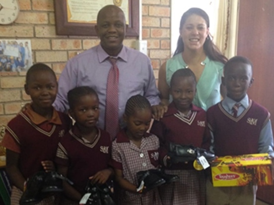 St. Mary’s School Principal Victor Sekakatlela, with students and a teacher, giving out school uniforms.