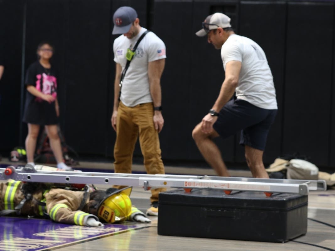 Golden’s Bridge Firefighter Saurabh Mehta (right) and another firefighter observed a student completing one of the challenges at last year’s “Trial by Fire” event at John Jay High School.