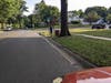 Eric stands beside No Parking and Bus Stop signs. Red car is properly placed, but cars can park up to the signs, which impedes the bus from stopping safely. If you're in a wheel chair, it's very bad news. (View is looking south, QV Blvd at Bluebird Terr)