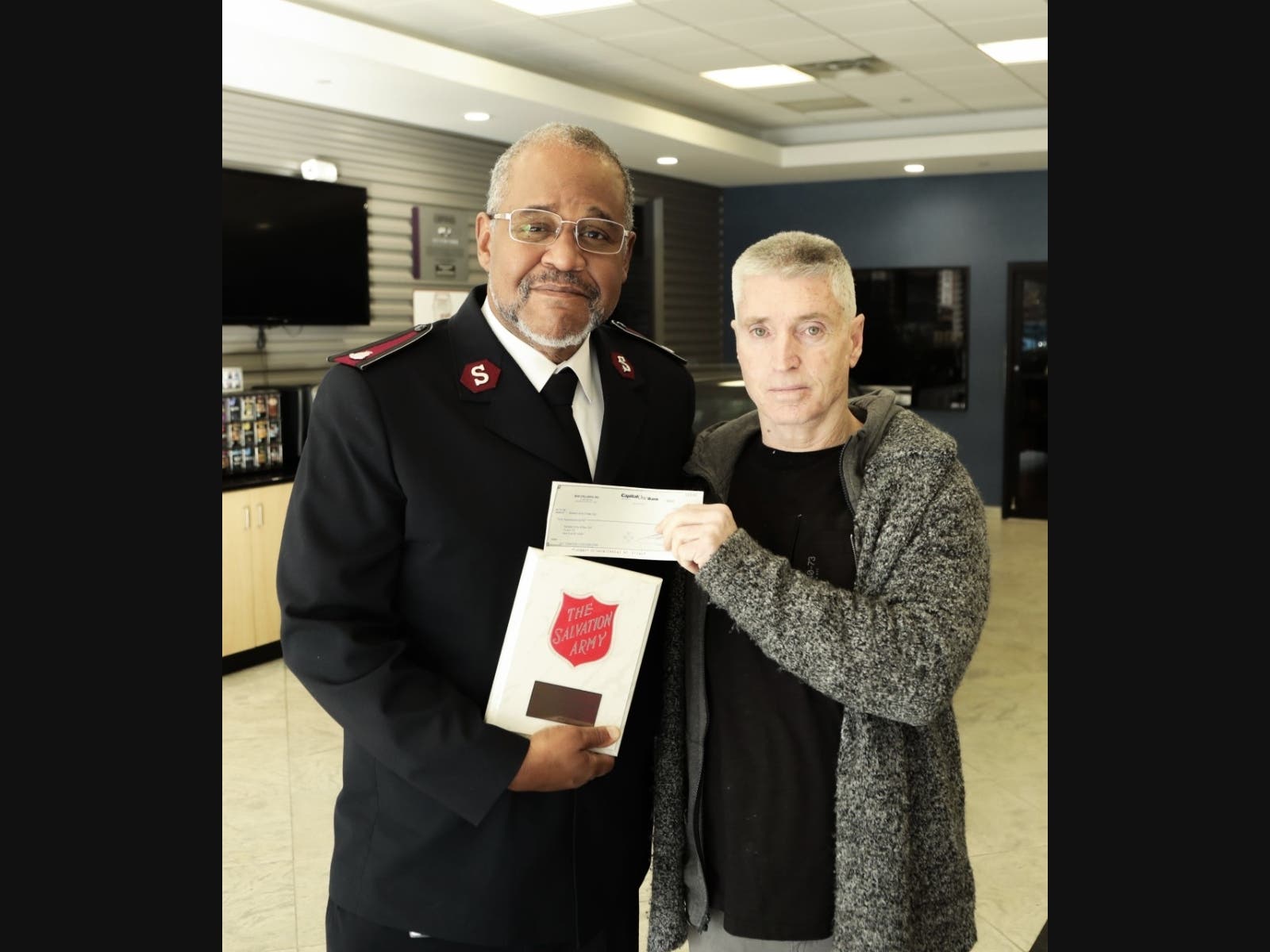 Bob Jesberger (right) gives a check to the Salvation Army and gets a plaque. 