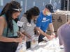 Katy Baez, Jessica Saturne and Americares SVP and Chief Marketing Officer Jed Selkowitz pack hygiene kits at a volunteer event at Americares global headquarters in Stamford, Conn., on Wednesday, June 8, 2022.