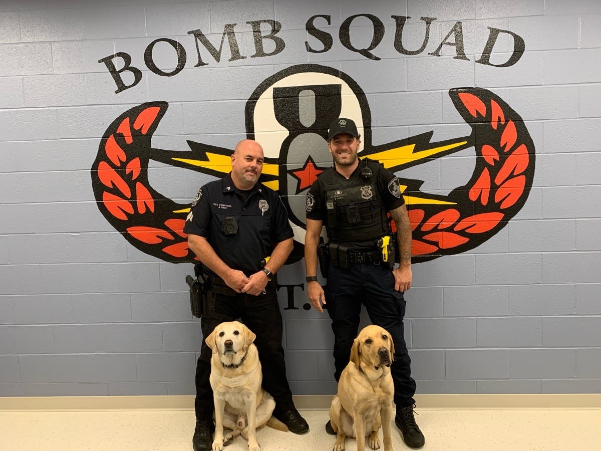 Sgt. James Comstock and K9 Pogo (left), next to officer Dan Kokkoros and K9 Kobe (right).